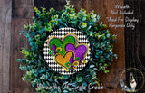 a wreath made of green and purple flowers, with a heart-shaped design in the center. The wreath is displayed on a wooden surface, and there is a small dog in the bottom right corner of the image.