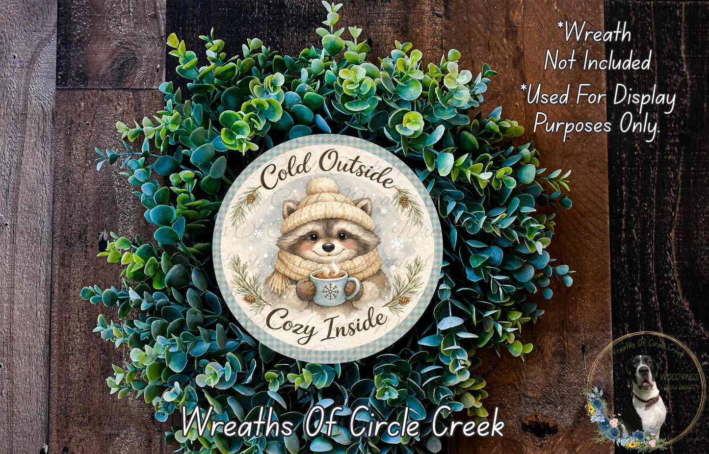 A wreath made of green leaves and a raccoon wearing a cozy hat, with the text "Cold Outside Cozy Inside" and "Wreaths of Circle Creek" displayed on it.