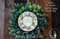 A wreath made of various green and blue foliage, with a circular sign in the center that reads "Merry Christmas Happy New Year". The wreath is displayed on a wooden surface, and there is a text overlay that says "Wreath Not Included * Used For Display Purposes Only".