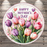 A round floral arrangement with pink and purple tulips, surrounded by green leaves, against a wooden background. The text "HAPPY MOTHER'S DAY" is displayed in the center of the image.