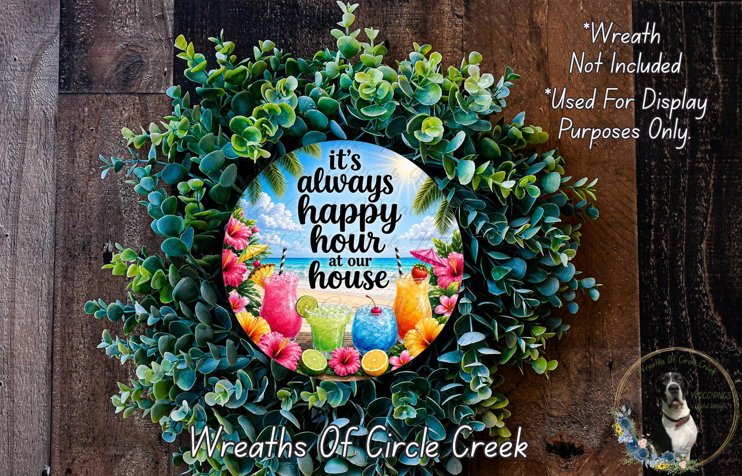 A wreath made of various green plants and colorful flowers, with a circular sign in the center that says "It's always happy hour at our house".