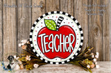 A decorative sign with the word "Teacher" written on it, surrounded by a wreath of flowers and a wooden background.