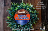 a wreath made of green foliage and a football, with the text "Tallaghties & Touchdowns" written on it. The wreath is displayed on a wooden surface, and there is a small dog in the bottom right corner of the image.