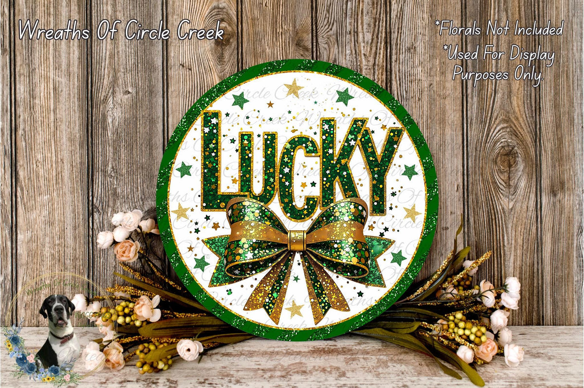 a circular sign with the word "Lucky" written on it, surrounded by a green and gold bow and a wreath of flowers.