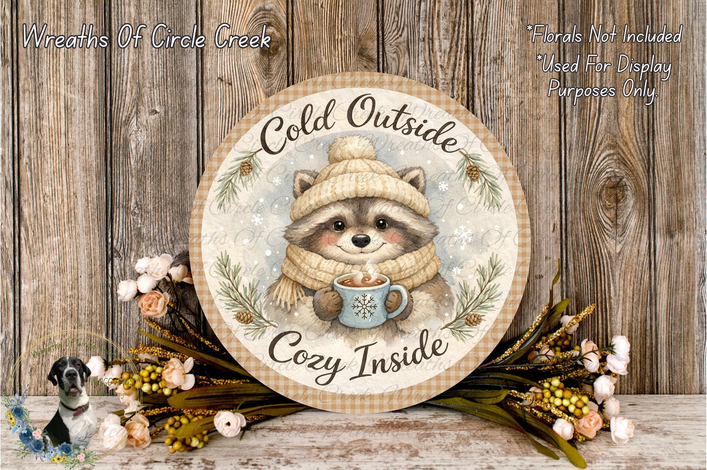A round wooden sign with a raccoon wearing a winter hat and scarf, holding a mug of hot chocolate, surrounded by flowers and greenery.