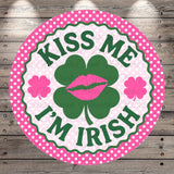 A circular sign with the text "KISS ME I'M IRISH" and a cloverleaf design, surrounded by pink polka dots.