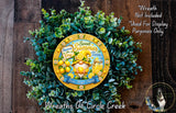 a wreath made of green leaves and a yellow plate with a gnome and lemon design, placed on a wooden surface.