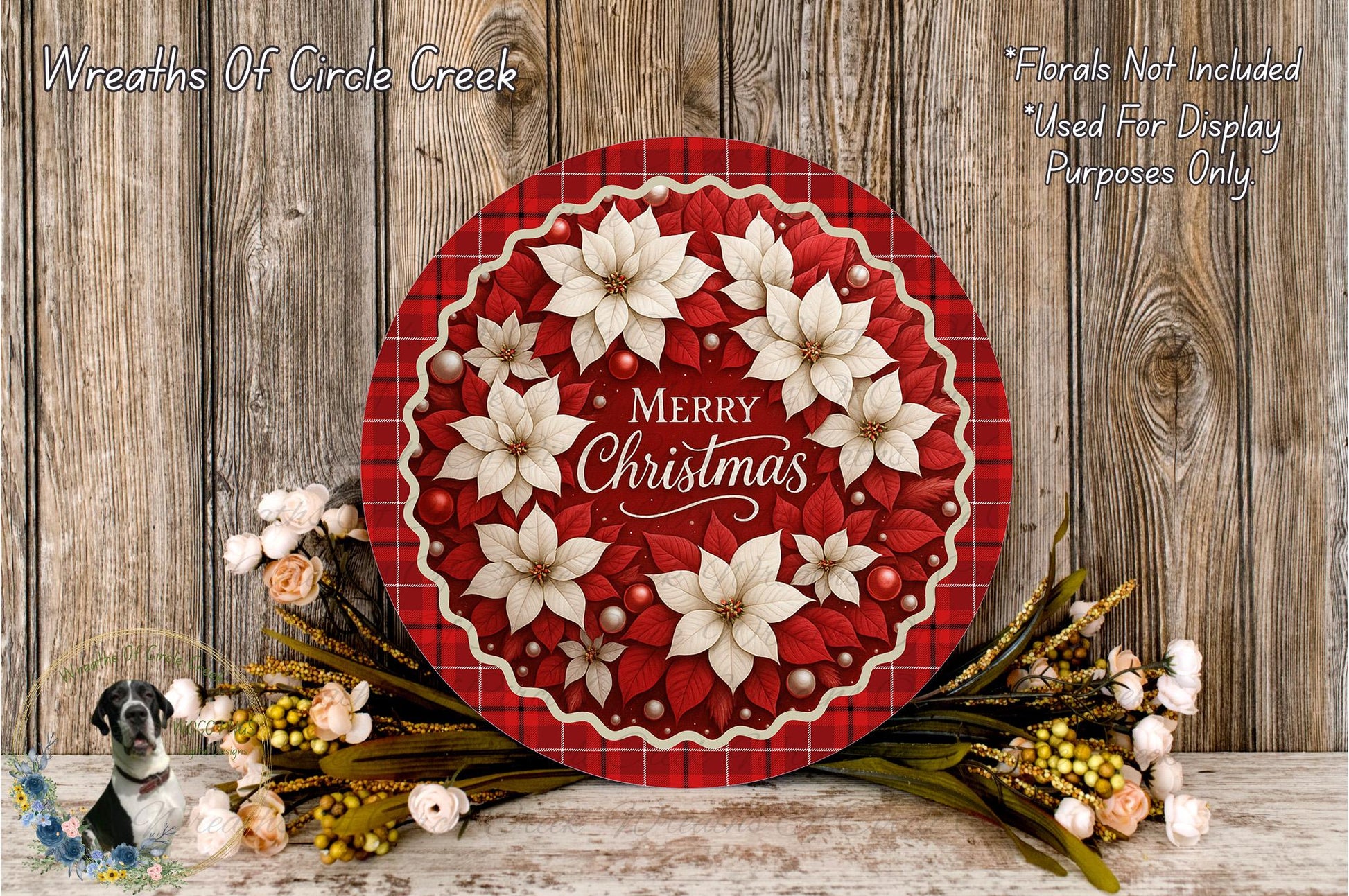 A festive Christmas wreath with white poinsettia flowers and red and white checkered border, placed on a wooden surface. The wreath is surrounded by a variety of flowers and greenery, creating a beautiful holiday display.