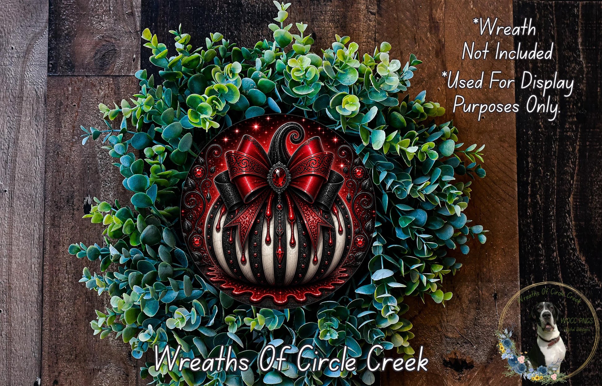 a wreath with a red bow and a pumpkin-shaped ornament, surrounded by green foliage. The wreath is displayed on a wooden surface, and there is a small dog in the bottom right corner of the image.