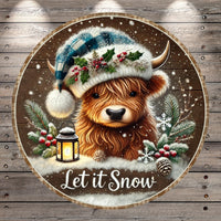 A close-up of a brown cow wearing a blue and white plaid hat with holly leaves and berries, surrounded by snow, pine branches, and a lantern, with the text "Let it Snow" below.