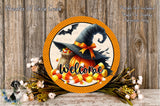 a Halloween-themed wreath with a witch's hat, candy corn, and a "Welcome" sign. The wreath is displayed on a wooden surface, surrounded by flowers and a spooky bat decoration.