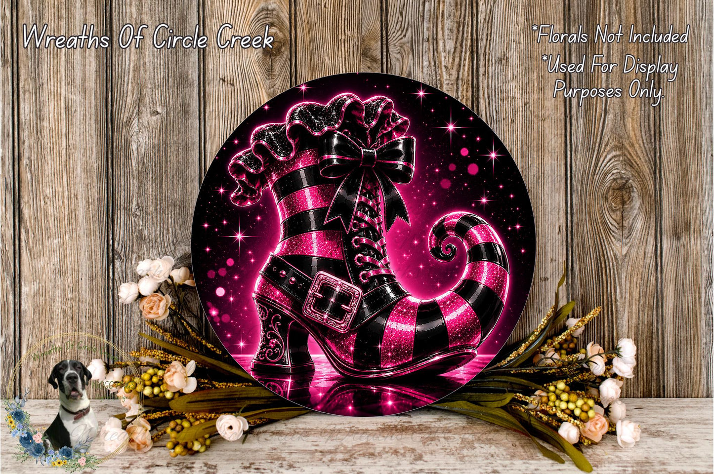 A decorative wreath featuring a large, glittery black and pink striped boot as the centerpiece, surrounded by flowers and placed on a wooden surface.