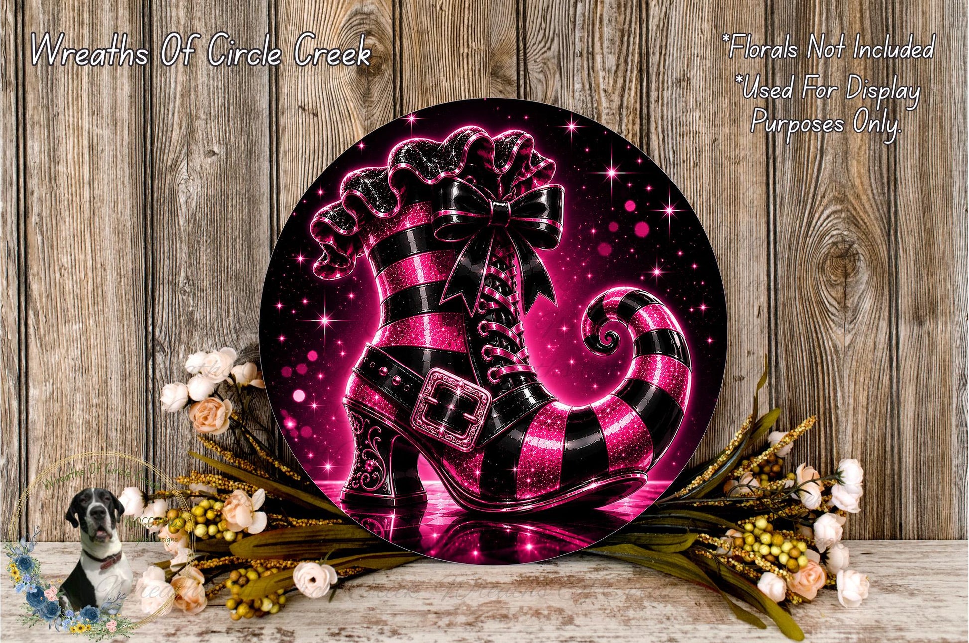 A decorative wreath featuring a large, glittery black and pink striped boot as the centerpiece, surrounded by flowers and placed on a wooden surface.