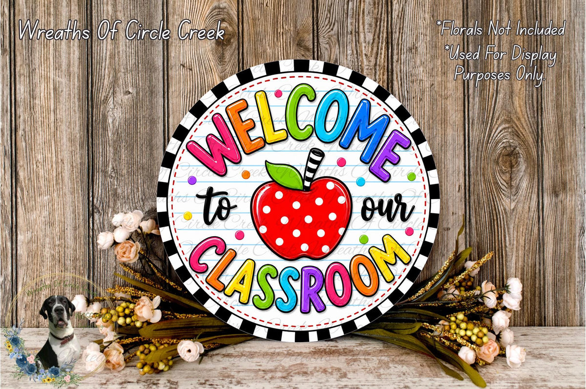 A colorful welcome sign for a classroom, featuring a red apple with polka dots and the text "Welcome to our Classroom" in a circular design.
