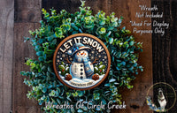 A wreath made of green leaves and a snowman decoration, with the text "LET IT SNOW somewhere else" displayed on it.