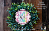 a wreath made of green leaves and flowers, with a decorative border and a text logo that reads "SAVED BY HIS GRACE".