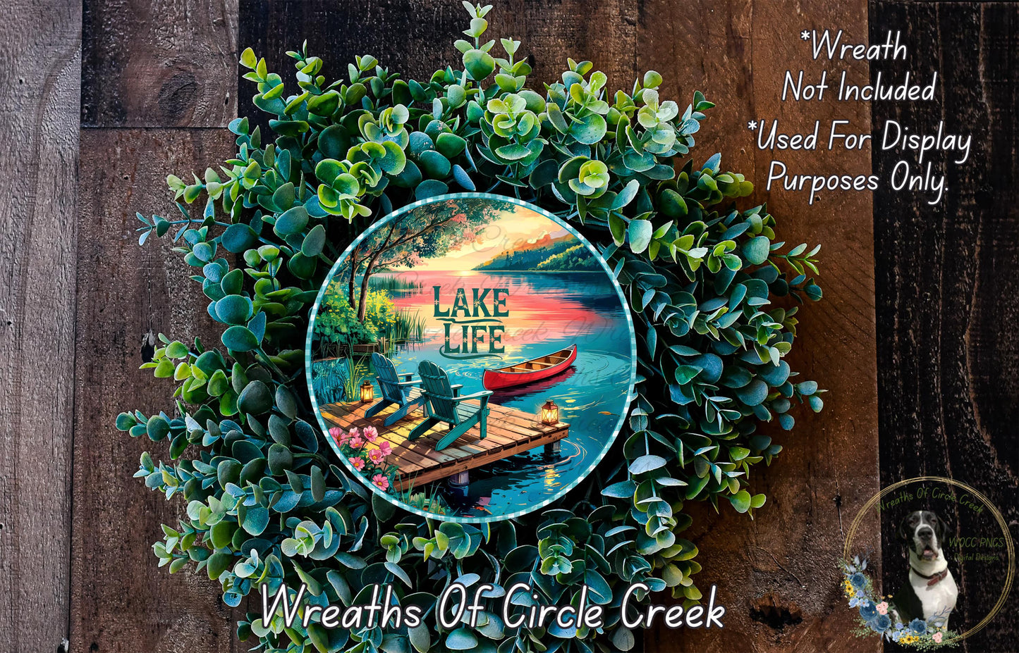 A wreath made of green leaves and flowers, with a circular design featuring a lake, dock, and boat, and the text "Lake Life" written on it.