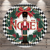 A nutcracker figure surrounded by a wreath of pine branches, berries, and greenery, with the word " Noel" prominently displayed in the center.