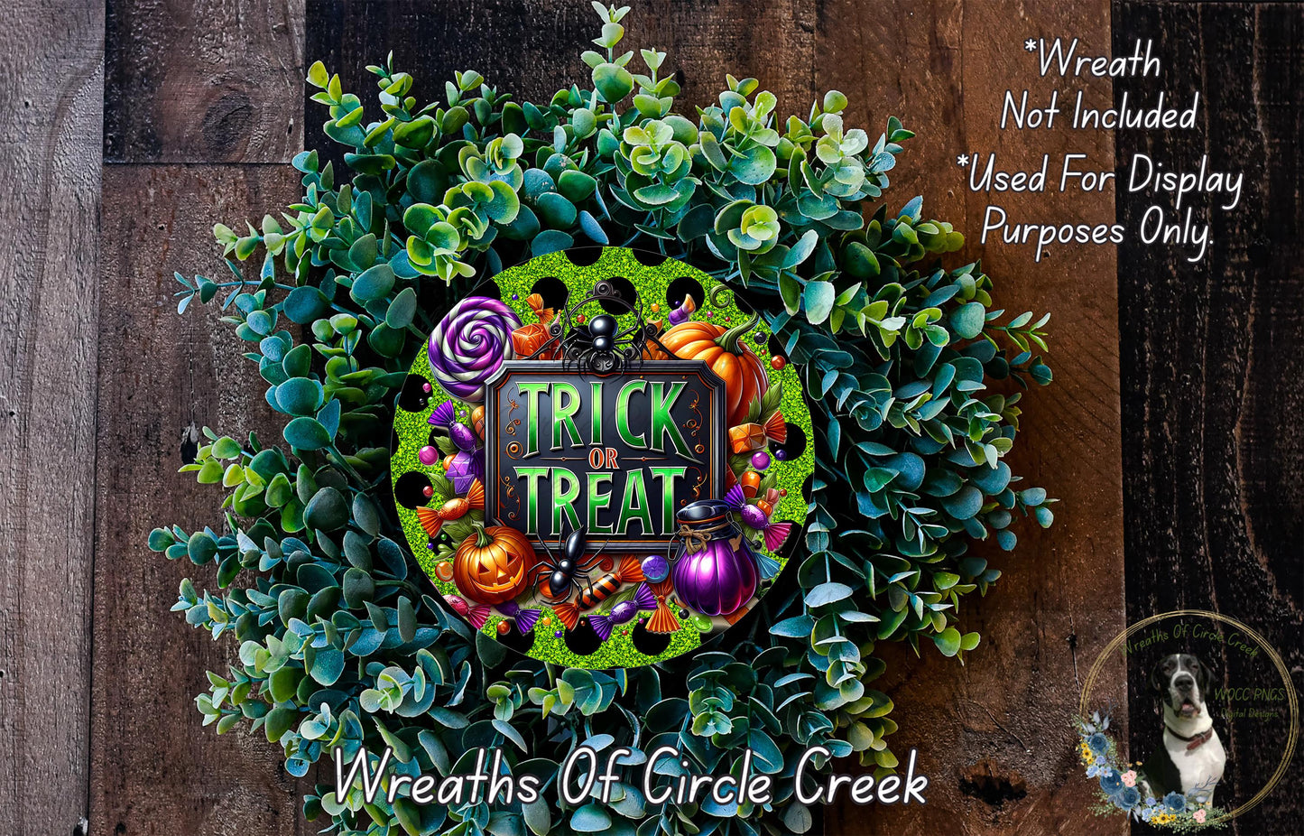 a wreath with the text "TRICK or TREAT" and various Halloween-themed decorations, including pumpkins, bats, and a spider. The wreath is set against a wooden background, and there is a small dog visible in the bottom right corner.