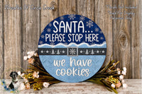 A circular sign with a blue background and white text, placed on a wooden surface with a floral arrangement in the foreground.