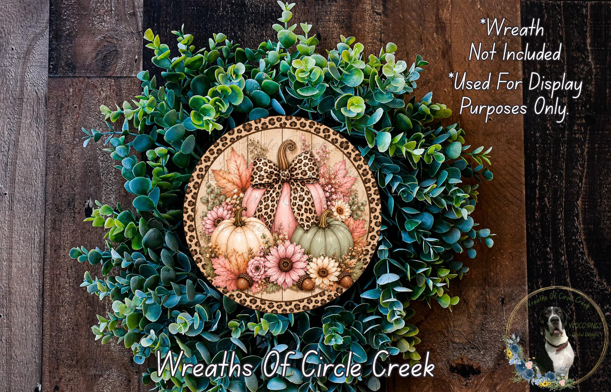 a wreath made of various plants and flowers, including pumpkins and greenery, hanging on a wooden wall.