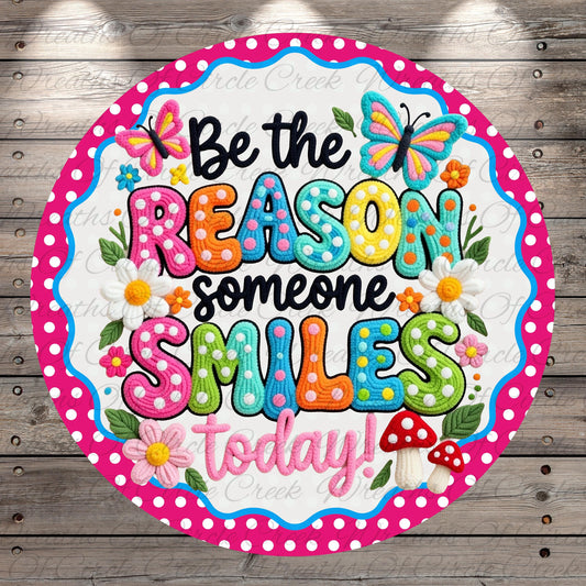 A colorful and whimsical sign with the text "Be the reason someone smiles today!" surrounded by flowers, butterflies, and mushrooms.