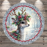 A deer with antlers and a holly wreath on its head is the central focus of the image, surrounded by a decorative border of red and silver glitter.