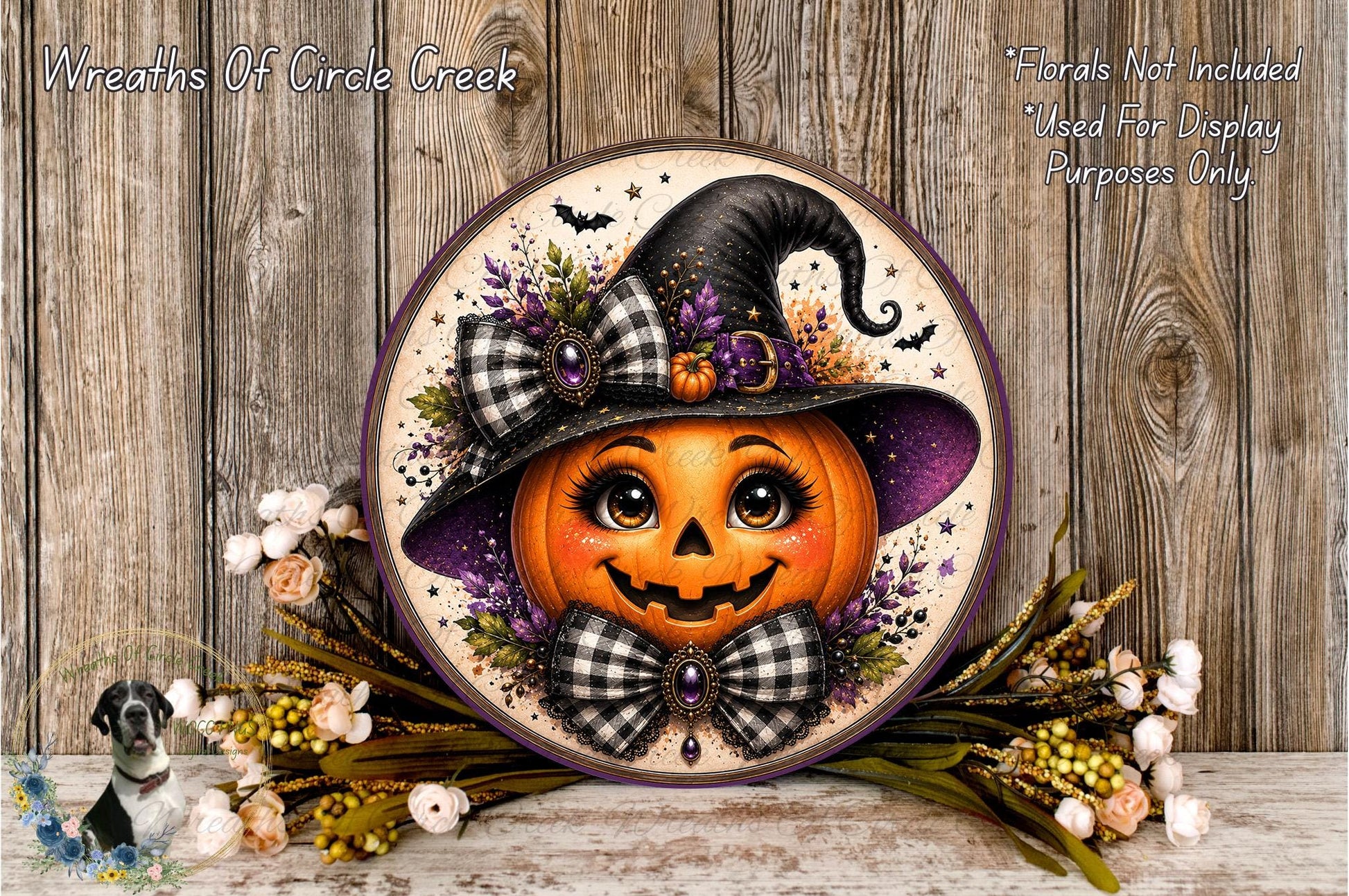 A Halloween-themed wreath featuring a carved pumpkin with a witch's hat and bow, surrounded by flowers and placed on a wooden surface.