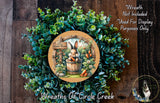 a wreath with a rabbit and carrots, surrounded by a lush green plant. The wreath is placed on a wooden surface, and there is a small dog in the bottom right corner of the image.