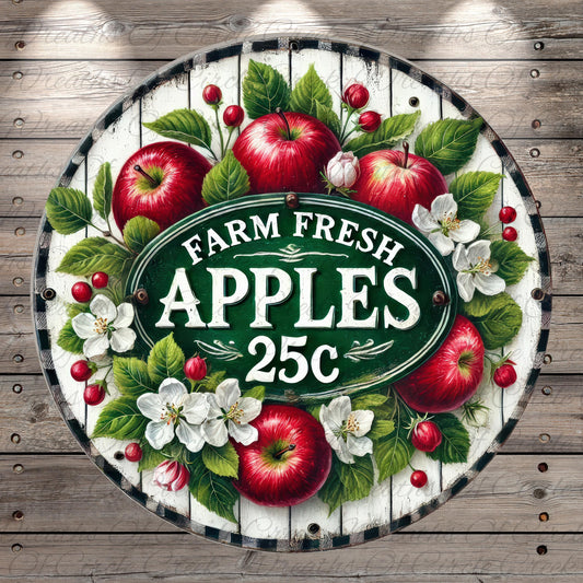 a circular sign with a white border and a green background, surrounded by a wreath of red apples, white flowers, and green leaves. The sign prominently displays the text "FARM FRESH APPLES 25c".