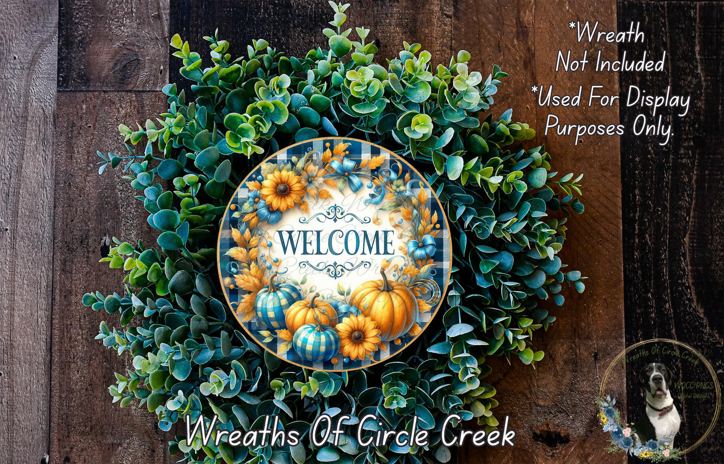 a wreath made of various green and orange foliage, with a central circular design that says "WELCOME". The wreath is displayed on a wooden surface, and there is a small dog in the bottom right corner of the image.