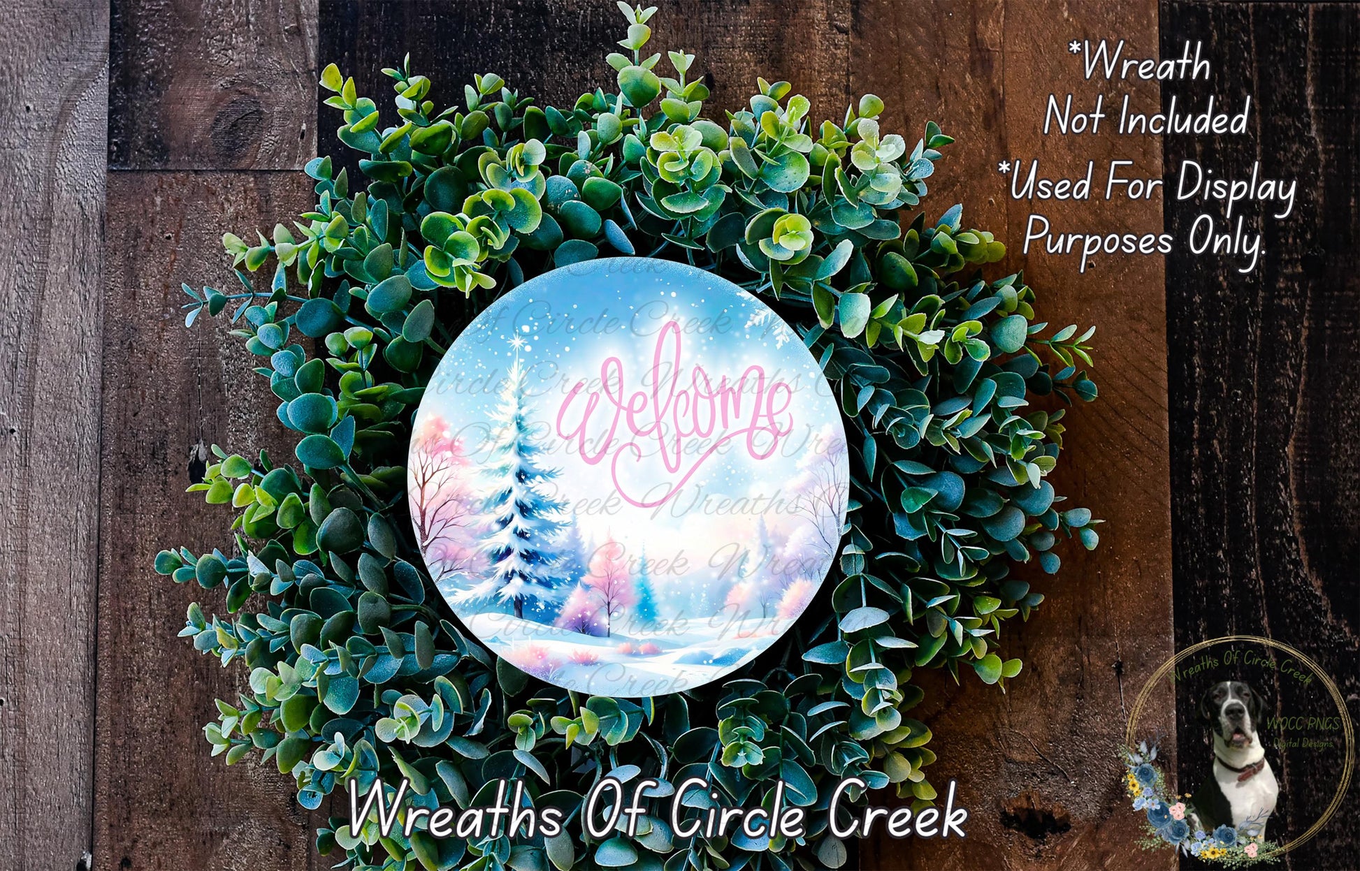 A wreath made of green leaves and branches, with a circular sign featuring a winter landscape and the word "Welcome" in the center.