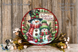 A decorative snowman and a snowman decoration with a red and white striped scarf, surrounded by a wreath of flowers and greenery, against a wooden background.