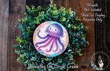 A wreath made of green plants and a purple jellyfish design, with a text overlay that reads "Wreath Not Included * Used For Display Purposes Only" and "Wreaths of Circle Creek".