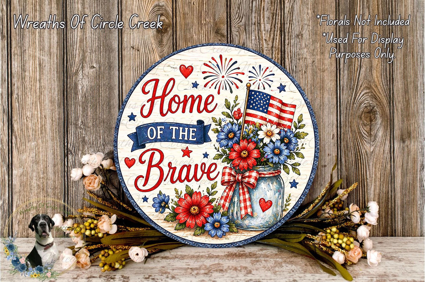 A patriotic sign that reads "Home of the Brave" with an American flag and flowers, placed on a wooden surface.