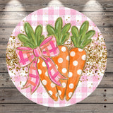 A circular decorative piece featuring three orange carrots with green leaves, each adorned with a pink bow, set against a pink and white checkered background with gold glitter accents.