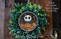 A Halloween-themed wreath made of green foliage and featuring a skeleton figure holding a jack-o-lantern.