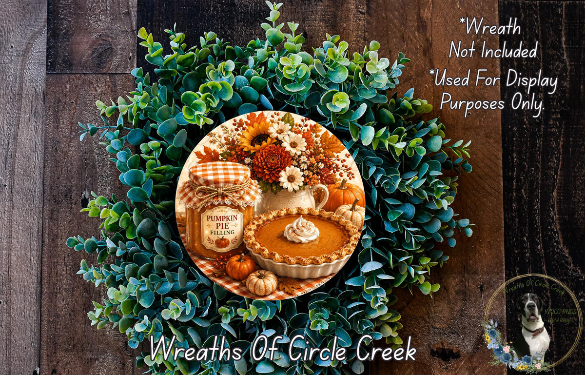 A wreath made of green leaves and flowers, with a pumpkin pie and other fall-themed items displayed on it.