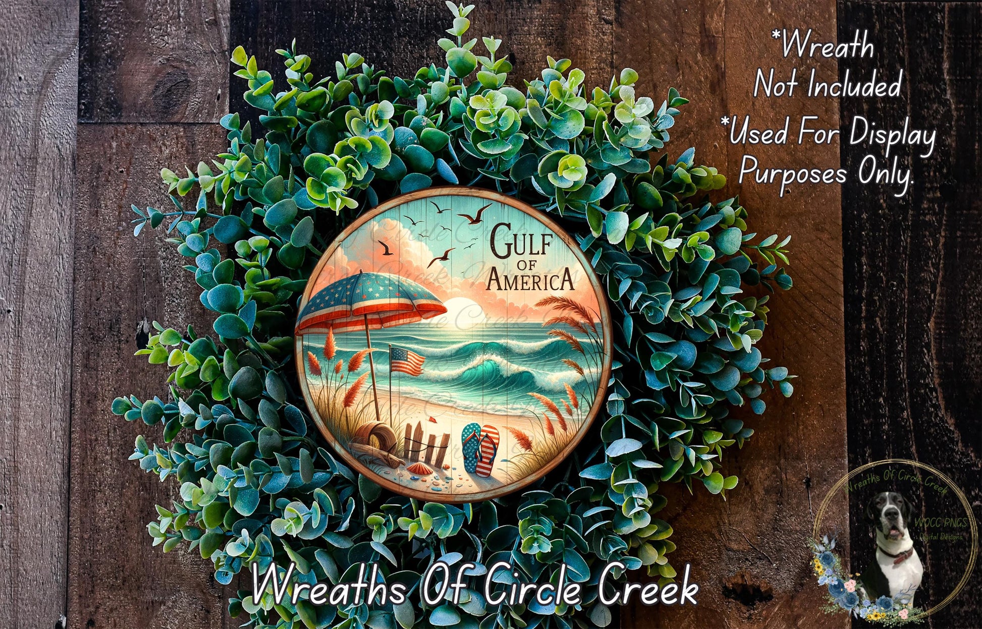 A wreath made of green foliage, featuring a circular design with a beach scene and an American flag. The wreath is displayed on a wooden surface, and there is a text overlay that reads "Wreath Not Included * Used For Display Purposes Only".
