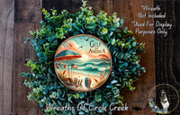 A wreath made of green foliage, featuring a circular design with a beach scene and an American flag. The wreath is displayed on a wooden surface, and there is a text overlay that reads "Wreath Not Included * Used For Display Purposes Only".