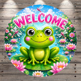 A round, colorful sign featuring a smiling frog sitting on a lily pad surrounded by pink flowers, with a blue sky and fluffy clouds in the background.