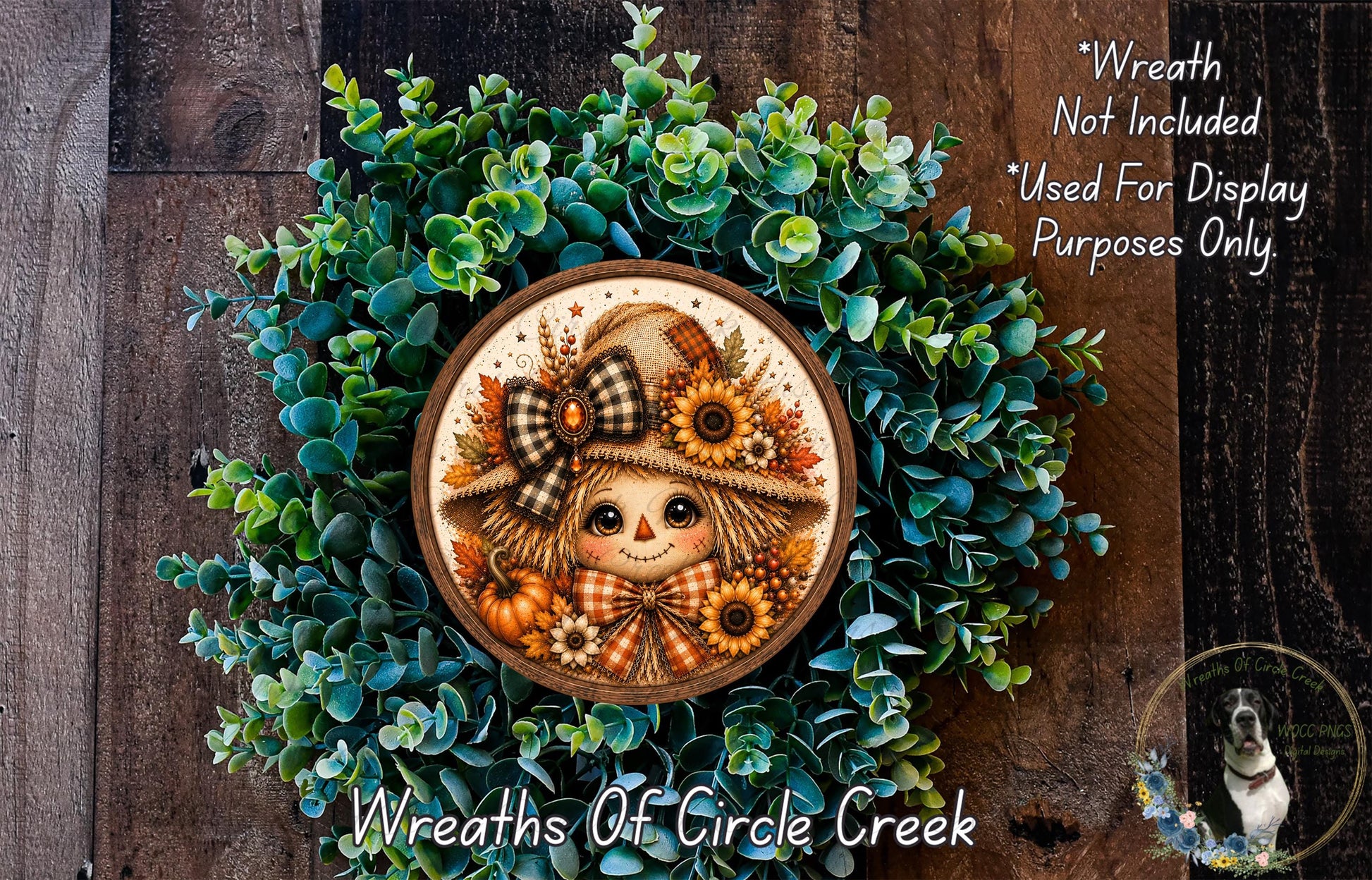 a wreath with a scarecrow design, surrounded by green foliage. The wreath is placed on a wooden surface, and there is a small dog in the bottom right corner of the image.