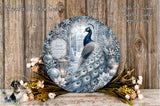 A decorative plate featuring a peacock surrounded by a winter wonderland scene, with a snowy landscape, trees, and flowers.