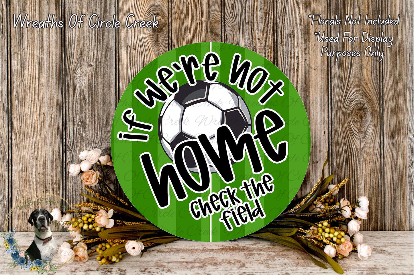 a green sign with the text "If we're not home, check the field" and a soccer ball graphic. The sign is surrounded by flowers and placed on a wooden surface.