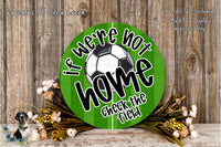 a green sign with the text "If we're not home, check the field" and a soccer ball graphic. The sign is surrounded by flowers and placed on a wooden surface.