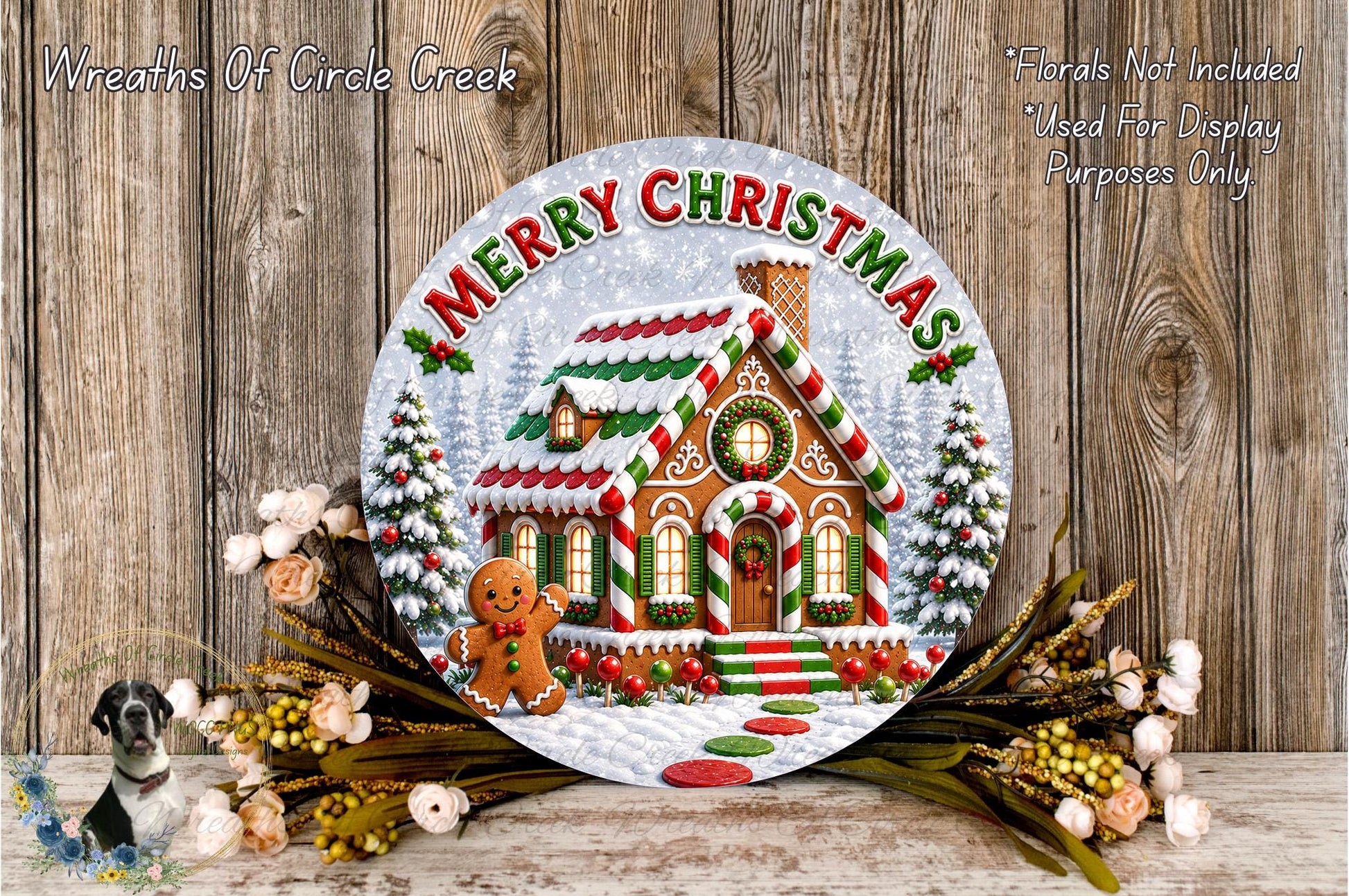 A festive Christmas wreath with a gingerbread house and a gingerbread man, surrounded by flowers and greenery, with the text "Merry Christmas" displayed on the wreath.