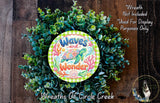 A wreath made of green and white leaves, with a colorful design featuring a turtle and the words "Waves and Wonder" written on it.