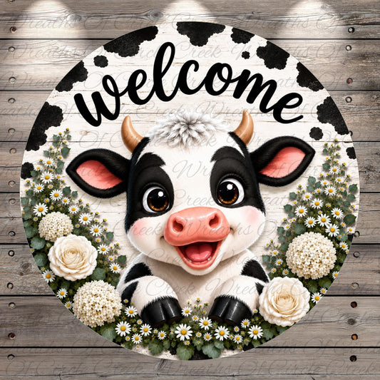 A black and white cow with horns is surrounded by white flowers and greenery, with the word "welcome" written above it.