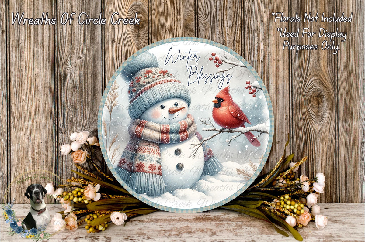 A snowman wearing a scarf and hat stands next to a red cardinal bird on a snowy branch, surrounded by a wreath of flowers and a wooden background.