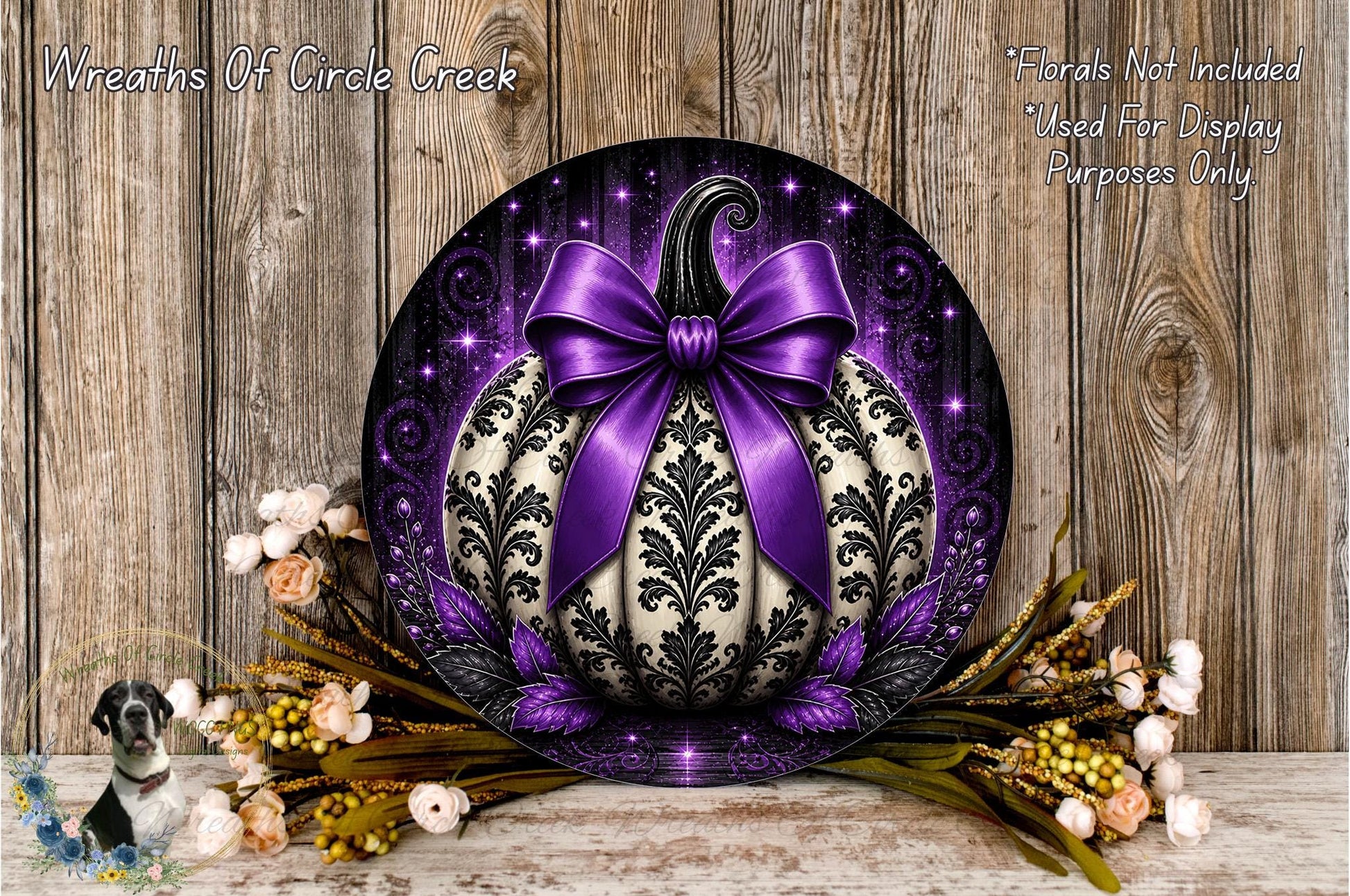 a decorative pumpkin with a purple bow, surrounded by flowers and placed on a wooden surface.